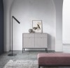 Jasnoszara ryflowana komoda ze złotymi uchwytami w minimalistycznym salonie z łukiem.