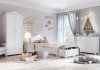Pokój dziecięcy dla dziewczynki z białymi meblami, dekoracyjnym księżycem i dziewczynką bawiącą się na podłodze.