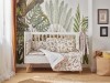 Przytulne łóżeczko dziecięce z pościelą w safari i fototapetą z motywem dużych tropikalnych liści.