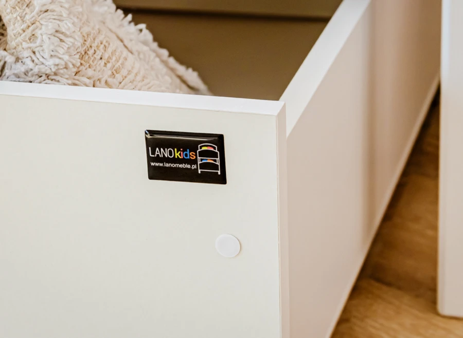 Logo LANOkids na białym elemencie łóżka, podkreślające jakość wykonania mebla.
