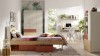 Pokój dziecięcy z łóżkiem, szafą i biurkiem. Meble dębowe z terakotowymi frontami i tapetą w liście.