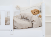 Przytulna aranżacja białego łóżka dziecięcego z beżową pościelą i misiem.
