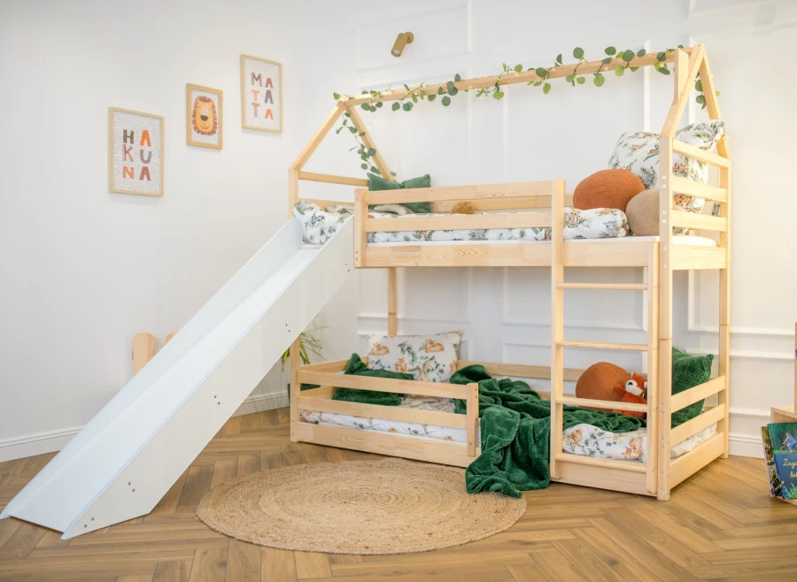Łóżko piętrowe domek ze zjeżdżalnią i drabinką w jasnym pokoju dziecka.