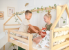 Szczęśliwe dzieci siedzące na piętrowym łóżku domek z miękką pościelą.