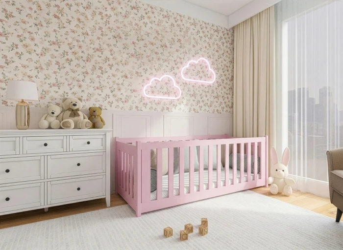 Różowe drewniane łóżeczko w jasnym pokoju dziecięcym z kwiatowym motywem na ścianie.