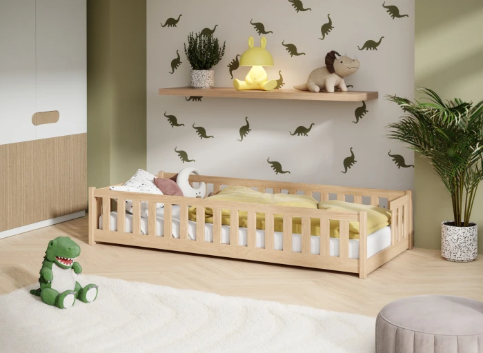 Niskie łóżko dziecięce montessori w pokoju z motywem dinozaurów.