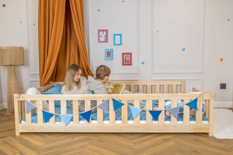 Pokój dziecięcy z drewnianym łóżkiem, baldachimem i mamą czytającą książkę z synem.